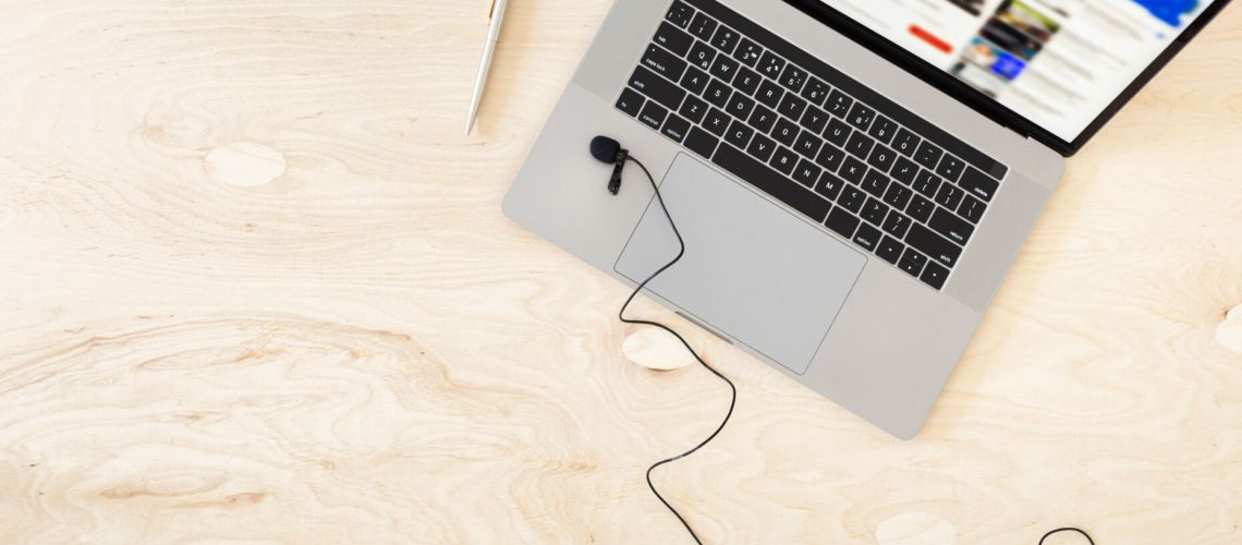 Online education or training course concept top view. Laptop with microphone on the table top view