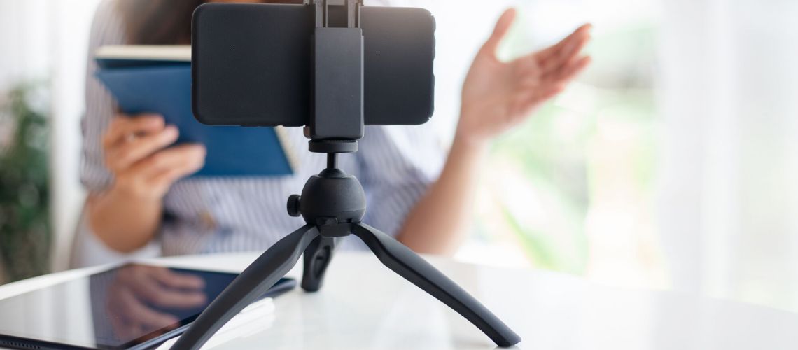 Young asian woman using mobile phone on small tripod live streaming to working or study online, concept  working with new normal and social distancing